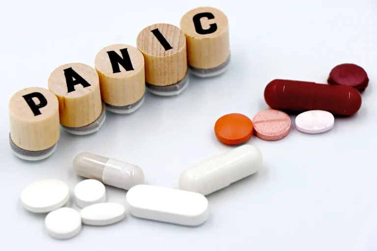 Houten blokken met het woord PANIC, omringd door pillen en capsules
